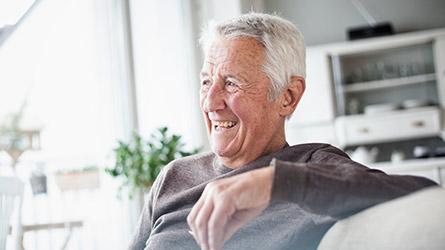 An elderly man sitting on his porch laughing 