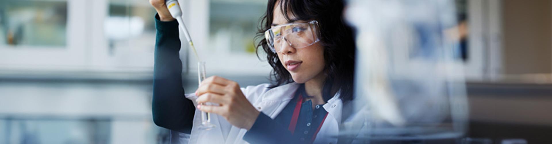 Eine Forscherin füllt ein Reagenzglas in einem Labor